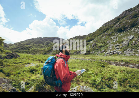 Hiker using digital tablet sur le paysage de campagne Banque D'Images
