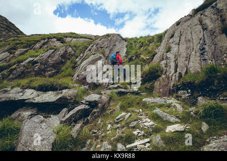 Randonneur gravir une montagne rocheuse sur paysage de campagne Banque D'Images