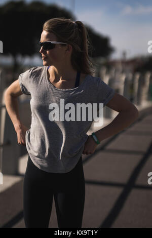 Woman runner standing on road portant des lunettes de soleil et bande de remise en forme Banque D'Images