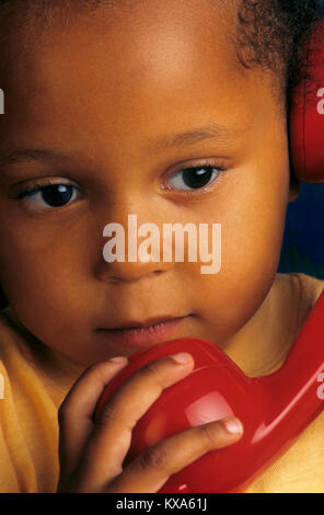 BÉBÉ TÉLÉPHONE MESSAGE PENSIVE DSA TÉLÉPHONE ENFANT COMBINÉ BÉBÉ AFRO Caraïbes 3-5 ans jolie fille attrayante à l'écoute sur son rouge combiné téléphonique Banque D'Images