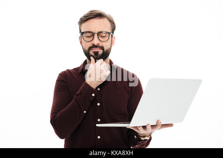 Portrait d'un homme barbu pensif holding laptop ordinateur isolé sur fond blanc Banque D'Images