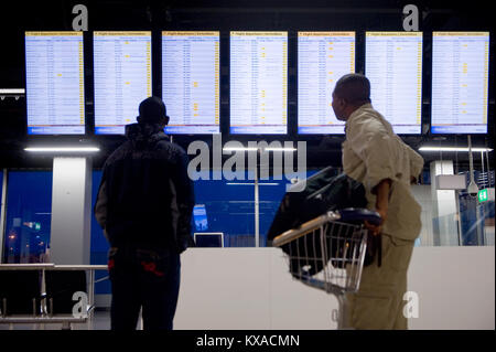 AMSTERDAM, Pays-Bas - DEC 27, 2017 : deux hommes sont à la recherche d'informations à l'écran pour contrôler son vol sur l'aéroport de Schiphol près d'Amsterdam Banque D'Images