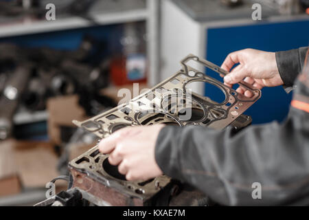 Le joint d'étanchéité du Main. Le mécanicien moteur bloc démontage véhicule. Moteur sur un banc de réparation avec le piston et la bielle de la technologie automobile. Intérieur d'un atelier de réparation de voiture. Banque D'Images