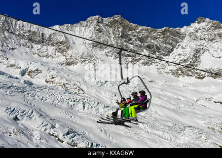 Skieurs sur un télésiège en face de l'Feegletscher et les pics Dom et Lenzspitze,Groupe,Mischabel Saas-Fee ski area,Valais Banque D'Images