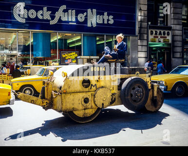 New York 1980s, homme conduisant un roadroller jaune, cale pleine de magasin o'NUTS, West 34th Street, Manhattan, New York City, NYC, NY, ÉTATS-UNIS, Banque D'Images