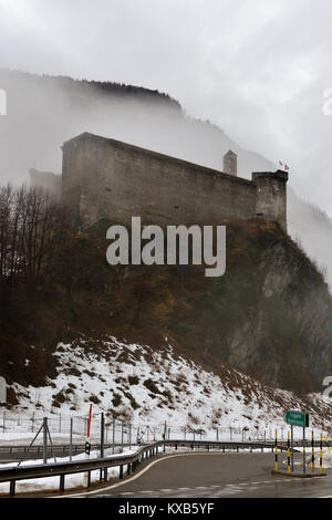 Château médiéval parmi les nuages bas qui menace la vallée de paysage d'hiver, tourné dans des conditions de ciel nuageux lumière à Poschiavo, Tessin, Suisse Banque D'Images