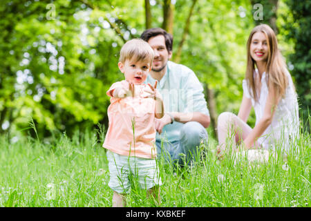 Petit garçon courir plus de prairie avec retour en famille Banque D'Images