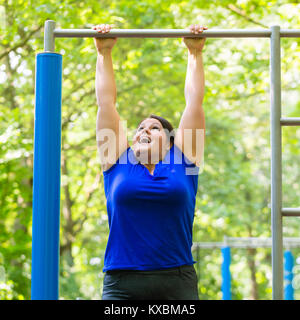 Femme potelée rendre le sport exercices au high bar Banque D'Images