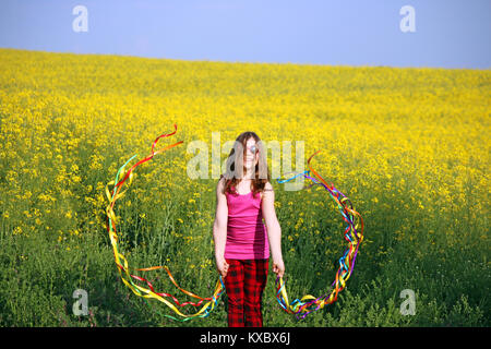 Happy little girl waving avec des rubans colorés sur terrain de la saison du printemps Banque D'Images