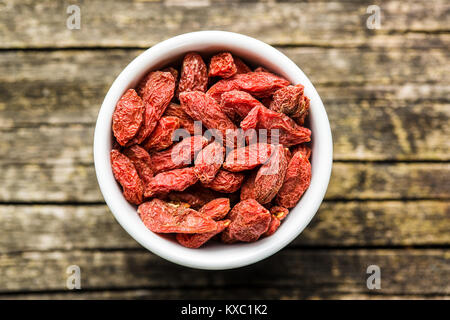 Baies de goji séchées dans un bol sur fond de bois. Banque D'Images