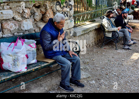 Plus de détente homme Grec, assis dehors sur un banc de travail avec les sacs, Athènes, Grèce Banque D'Images