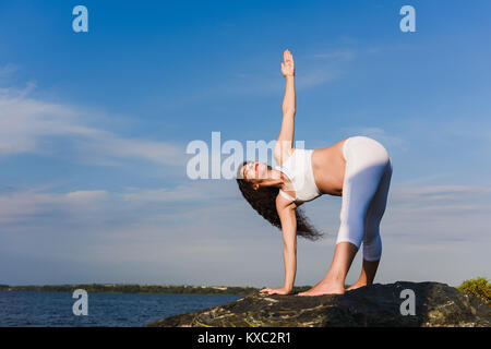 Femme enceinte est la pratique du yoga au bord de la rivière Banque D'Images