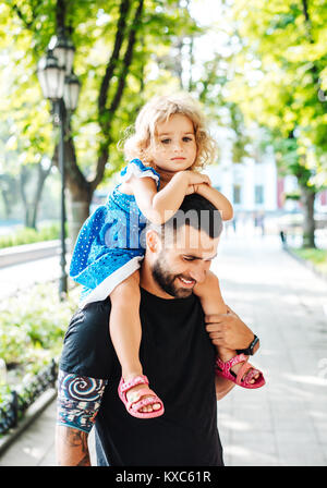 Petite fille à cheval sur les papas cou Banque D'Images