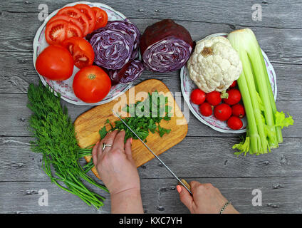 Femme coupe manuelle les verts pour une salade sur une planche à découper Banque D'Images