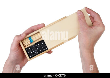 Le vieux grand-père ouvre une boîte en bois avec jeux de société - dominos et mikado. Isolated on white top view studio shot Banque D'Images