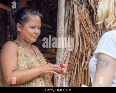 Iquitos, Pérou- le 14 décembre 2017 : femme de la tribu Yahuas dans son costume local. Elle est puting ligne rouge sur la face de l'église. Banque D'Images