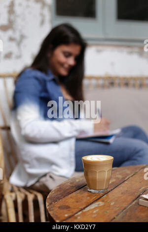 Femme écrit avec du café sur la table en premier plan Banque D'Images