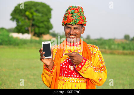 1 Rural Indien Gujrati Villager Man Pointing Téléphone Mobile Banque D'Images