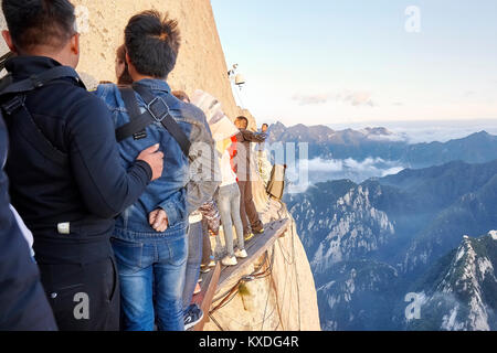 Le Mont Hua, Province de Shaanxi, Chine - 6 octobre 2017 : les touristes sur la planche à pied dans le ciel au coucher du soleil, les mondes les plus dangereux de la randonnée. Banque D'Images