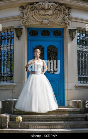 Jeune femme blonde en robe de mariée blanche pose sur escaliers, Suisse Banque D'Images
