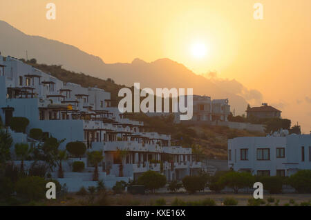 Coucher du soleil derrière les montagnes avec des maisons construire contre la montagne à Kyrenia, Chypre Banque D'Images