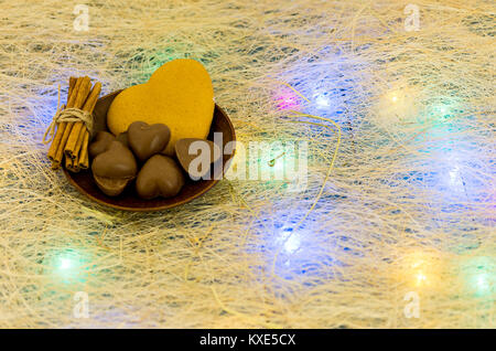 Une assiette avec des bonbons en forme de cœur. Guirlande multicolore. Le jour de la Saint-Valentin. Banque D'Images