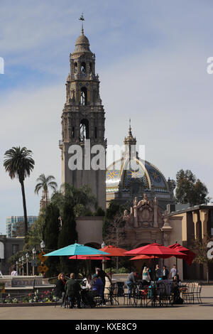 La magnifique Tour de Californie et le dôme du Musée de l'homme pèsent sur les visiteurs assis sous des parasols colorés dans Balboa Park, San Diego, Californie Banque D'Images