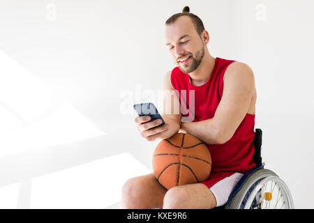 Joueur de basket-ball à mobilité using smartphone Banque D'Images