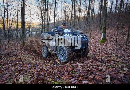 Jeune chasseur sur un quad à la recherche de jeu dans la forêt Banque D'Images