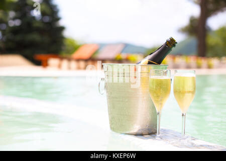 Verres de champagne et une bouteille dans un seau à glace près de la piscine. Vacances et romance concept Banque D'Images