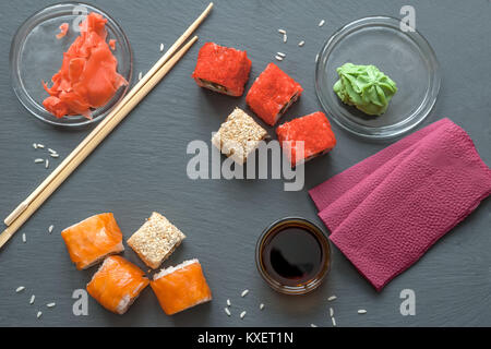 Les sushis japonais fait de riz et de loup de mer, la crevette et l'anguille fumée avec caviar de poisson volant avec du fromage Philadelphia, baguettes sur la plaque noire avec de la sauce soja, gingembre et wasabi Banque D'Images