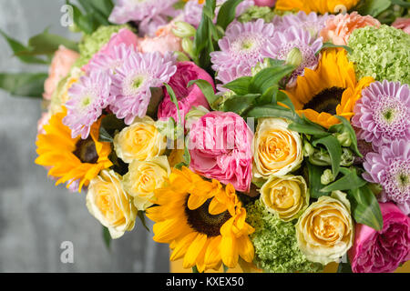 Beau bouquet de fleurs dans un vase sur la table en bois. le travail du fleuriste dans un magasin de fleurs. un brillant mélange de tournesols, chrysanthèmes et roses Banque D'Images