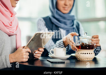 Musulmane femelle college student using tablet computer in cafe Banque D'Images