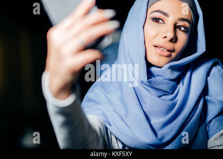 Femme musulmane arabe en tenant avec selfies téléphone dans cafe Banque D'Images