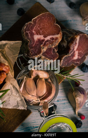 Photo verticale avec vue de dessus sur l'italienne empilés la viande provenant de porcs sangliers placé sur bleu et blanc vintage bois sec de couleur avec de l'ail, ber Banque D'Images