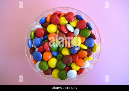 Bonbons multicolores dans un bol de cristal sur un fond uni Banque D'Images