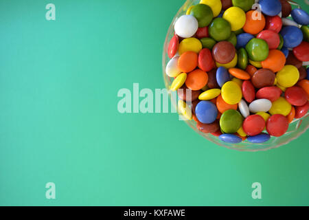 Bonbons multicolores dans un bol de cristal sur un fond uni Banque D'Images