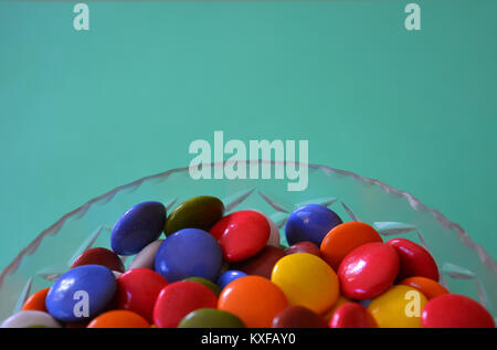 Bonbons multicolores dans un bol de cristal sur un fond uni Banque D'Images