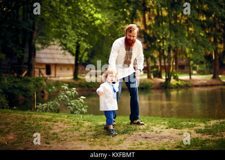 Red-entendu père et fils rouge-entendu s'amusant dans un parc dans une chemise blanche traditionnelle avec ornement Banque D'Images