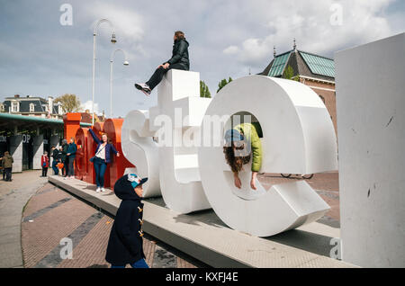 Amsterdam, Pays-Bas - avril 27,2017 : la diversité des touristes d'interagir avec d'énormes lettres I Amsterdam - symbole de la ville. Banque D'Images