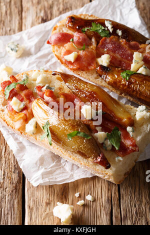 Des sandwichs avec du pain rustique avec du Roquefort, échalotes caramélisées et oignon persil frais sur table en bois libre verticale. Banque D'Images