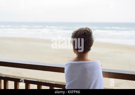 Boy looking at view tout en étant enveloppé dans une serviette Banque D'Images