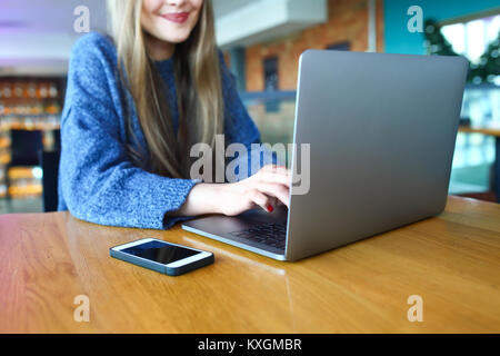 Woman working on laptop dans un café. Jeune femme assise à une table avec une usinglaptop. Avec copie vierge d'éboulis de l'espace pour votre publicité message texte ou image aux couleurs de contenu promotionnel. Focus sélectif. Banque D'Images