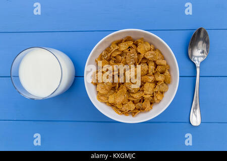 Flocons de céréales petit déjeuner bol avec du lait sur fond de table en bois bleu Banque D'Images