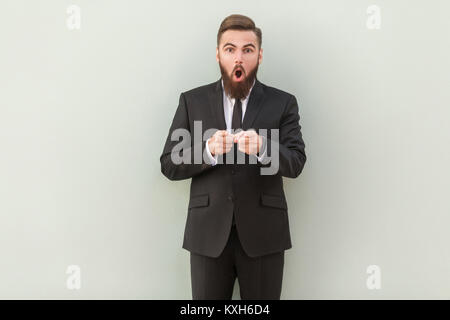 Portrait de l'homme d'affaires barbu, avec le choc de l'expression du visage. Pointer du doigt et appareil photo avec de grands yeux et ouvrir la bouche. Studio shot Banque D'Images