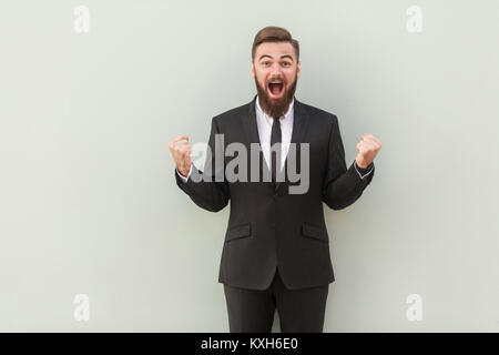 La victoire. L'homme d'affaires barbu jeunes adultes faisant un geste gagnant. Studio shot Banque D'Images