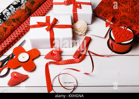 Boîtes cadeaux enveloppés dans du papier blanc et des rubans rouges, des coeurs, des bougies, et un plan de travail pour l'emballage de cadeau de fête pour la Saint-Valentin, Noël, Nouvel Banque D'Images