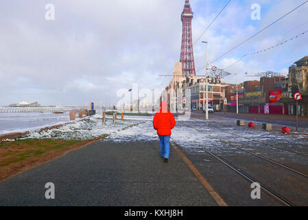 L'homme en manteau rouge à marcher le long du front de mer de Blackpool pendant une tempête Banque D'Images