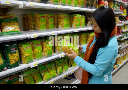 Portugal, Algarve, Monchique, Circa 10 décembre 2013. Jeune femme choisissant de pâtes pour la vente dans un supermarché. Banque D'Images