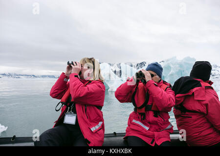 G Adventures passagers de navires de croisière observation de la faune à l'aide de jumelles sur un zodiac canot dans les eaux de l'Arctique glacial. Spitsbergen, Svalbard, Norvège Banque D'Images